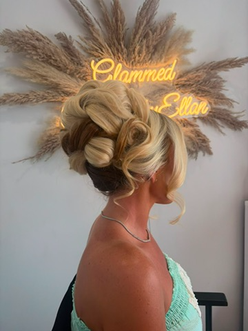 Blonde pin-curl updo under the studio neon sign